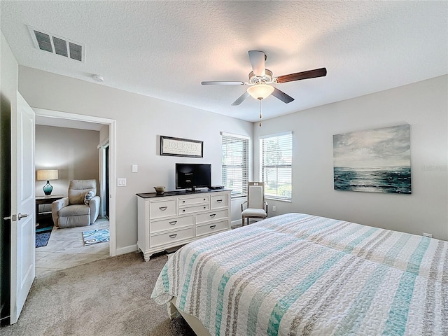 bedroom with light carpet, a textured ceiling, and ceiling fan