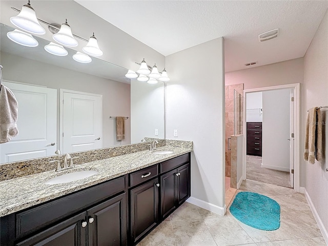 bathroom with tile patterned flooring, vanity, and a textured ceiling