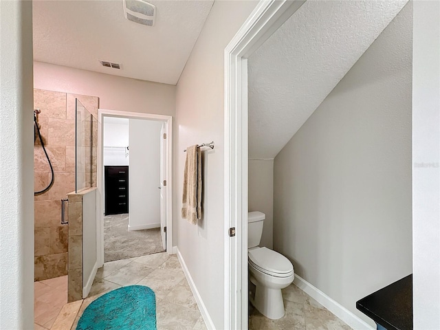 bathroom with a shower with door, tile patterned flooring, a textured ceiling, and toilet