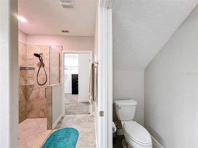 bathroom with tile patterned flooring, toilet, a shower with shower door, and a textured ceiling