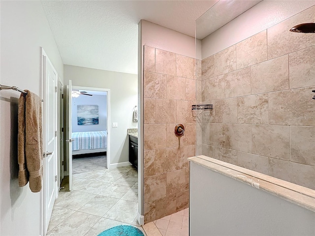 bathroom with a tile shower, tile patterned flooring, vanity, and a textured ceiling