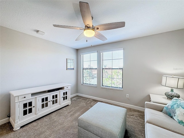 carpeted living room featuring ceiling fan and a textured ceiling