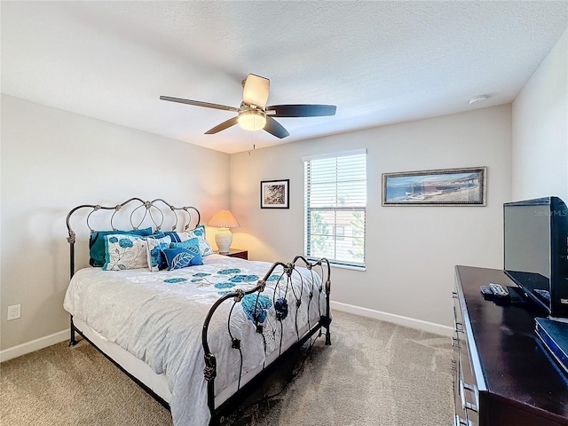 bedroom featuring ceiling fan, light colored carpet, and a textured ceiling