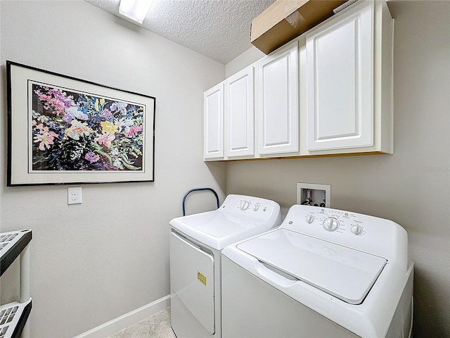 laundry area with washer and clothes dryer, cabinets, light tile patterned floors, and a textured ceiling