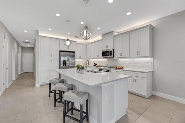 kitchen with a center island with sink, appliances with stainless steel finishes, a breakfast bar area, light countertops, and a sink