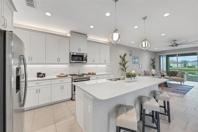 kitchen with stainless steel appliances, a sink, visible vents, a kitchen bar, and pendant lighting