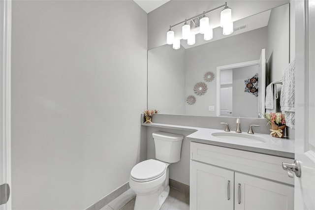 bathroom featuring baseboards, vanity, toilet, and tile patterned floors