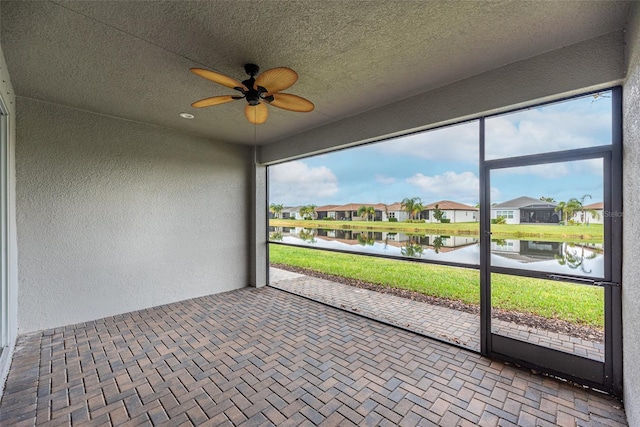 unfurnished sunroom featuring a water view, a residential view, and a ceiling fan