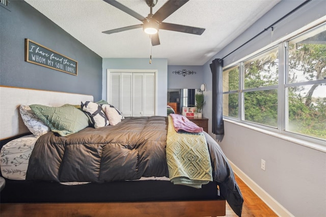 bedroom with ceiling fan, wood-type flooring, a textured ceiling, and a closet