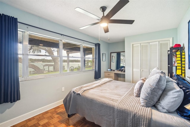 bedroom featuring a closet, ceiling fan, dark parquet floors, and a textured ceiling