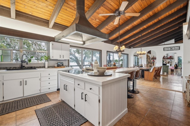 kitchen with white cabinets, sink, black cooktop, decorative light fixtures, and a kitchen island