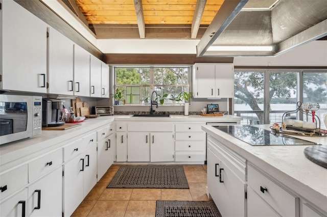 kitchen with black electric cooktop, white cabinetry, sink, and light tile patterned flooring