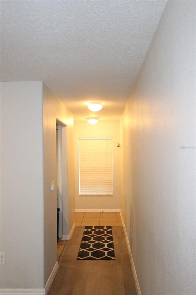 corridor with tile patterned flooring and a textured ceiling