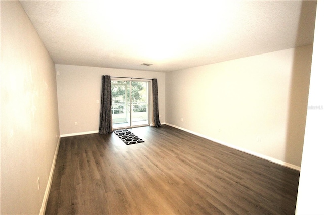 unfurnished room featuring dark wood-type flooring and a textured ceiling