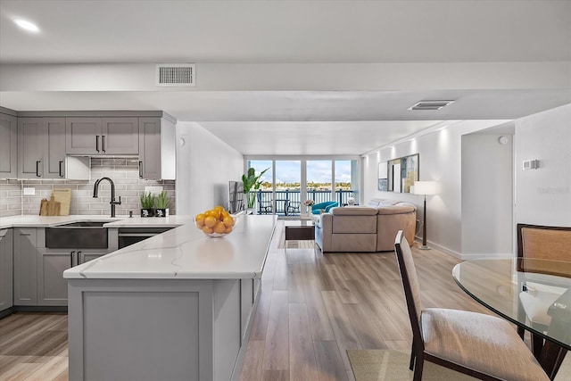 kitchen featuring gray cabinets, a kitchen island, light stone countertops, and light hardwood / wood-style flooring