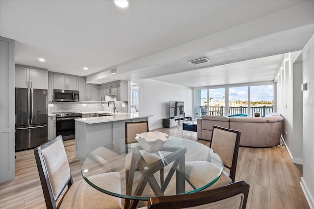 dining space with sink and light hardwood / wood-style flooring