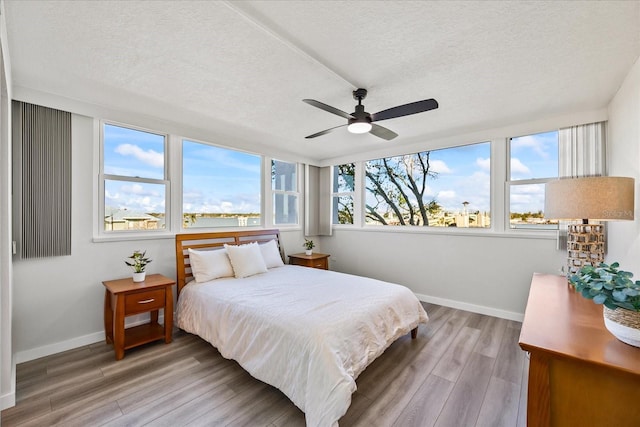 bedroom with ceiling fan, hardwood / wood-style floors, and a textured ceiling