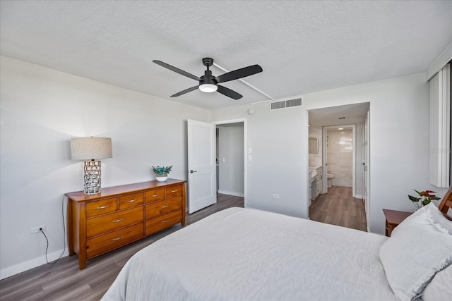 bedroom featuring ceiling fan, wood-type flooring, a textured ceiling, and connected bathroom