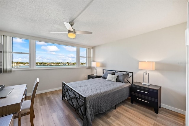 bedroom with hardwood / wood-style floors, ceiling fan, and a textured ceiling