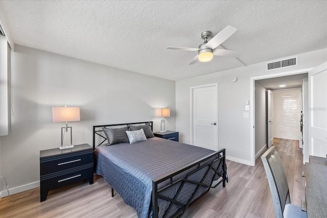 bedroom with ceiling fan, wood-type flooring, and a textured ceiling