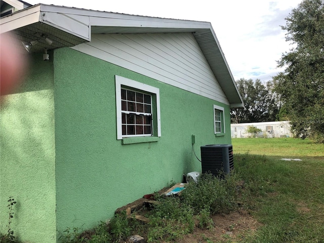 view of side of home featuring a lawn and central AC unit