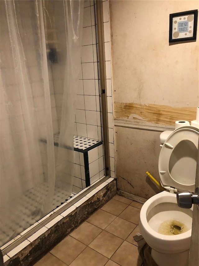 bathroom featuring tile patterned floors, toilet, and a tile shower