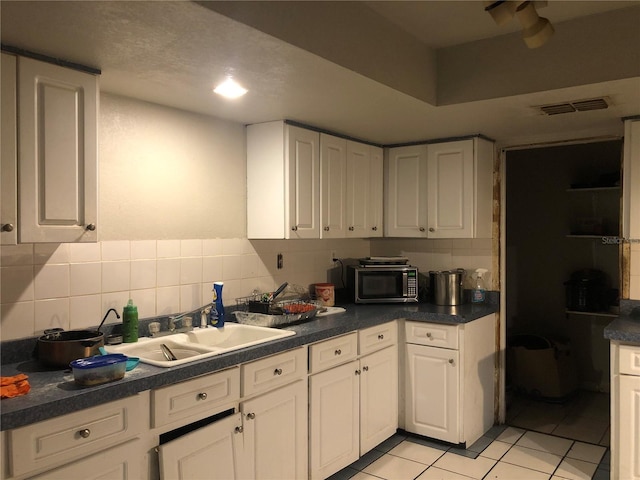 kitchen with tasteful backsplash, white cabinetry, and light tile patterned floors