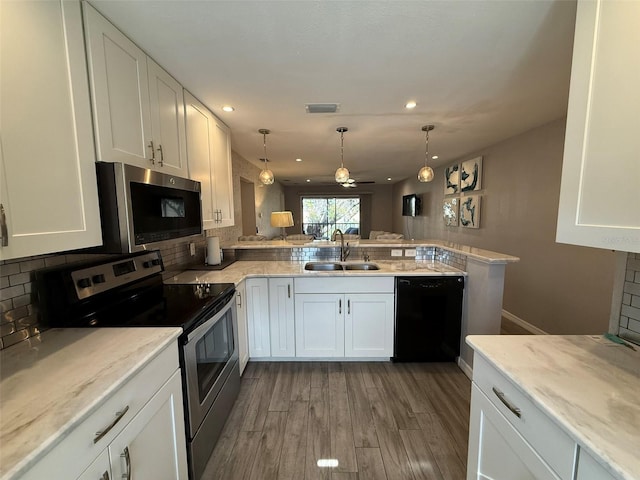 kitchen with kitchen peninsula, stainless steel appliances, sink, hardwood / wood-style floors, and white cabinetry