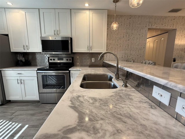 kitchen with pendant lighting, stainless steel appliances, white cabinetry, and sink