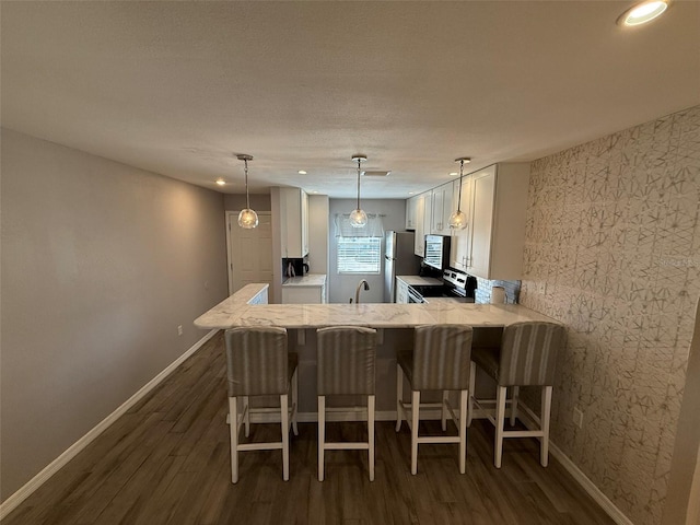 kitchen featuring kitchen peninsula, decorative light fixtures, dark hardwood / wood-style floors, stainless steel refrigerator, and range with electric stovetop