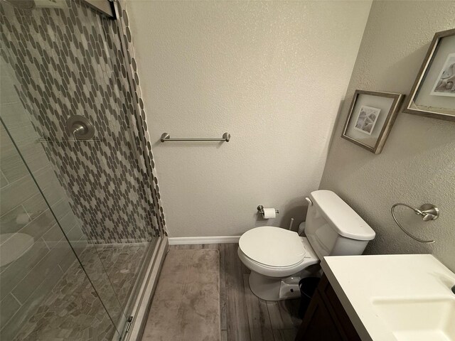 bathroom with wood-type flooring, vanity, toilet, and a shower with shower door