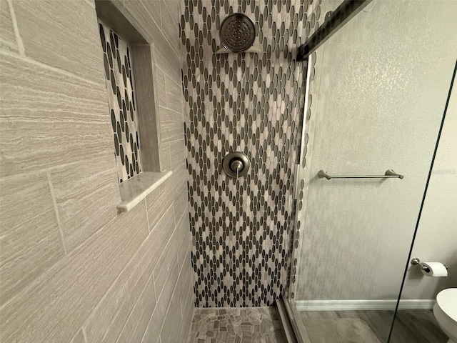 bathroom with a tile shower and toilet