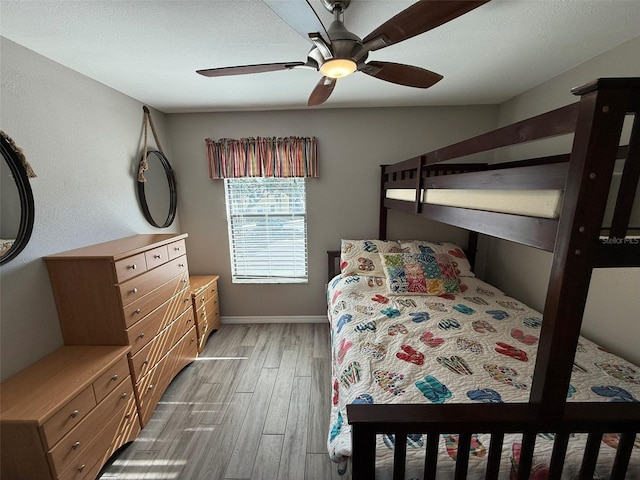 bedroom featuring ceiling fan, light hardwood / wood-style floors, and a textured ceiling