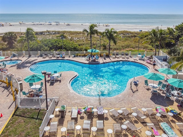 view of swimming pool featuring a water view, a patio, and a beach view