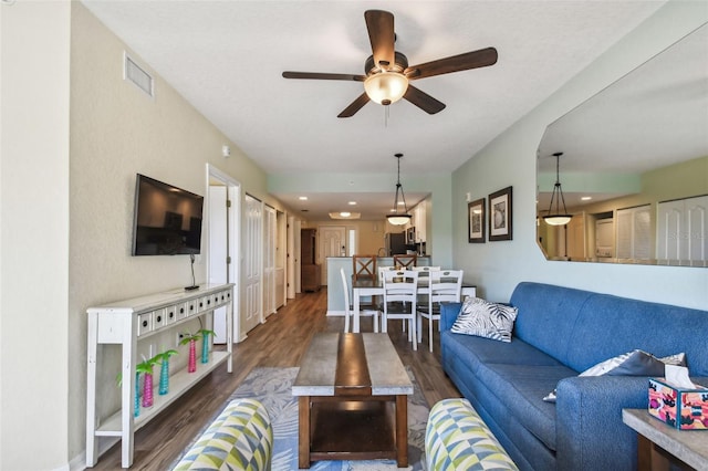 living room featuring ceiling fan and dark wood-type flooring