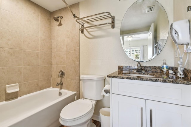 full bathroom featuring vanity, tiled shower / bath combo, and toilet