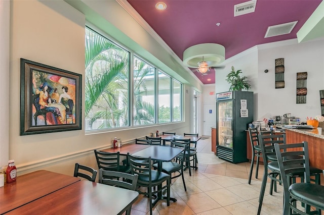 tiled dining area featuring ceiling fan and ornamental molding