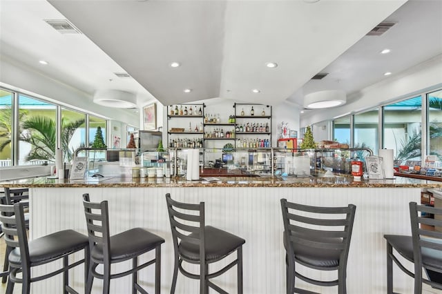 kitchen with a kitchen breakfast bar, lofted ceiling, crown molding, and stone counters