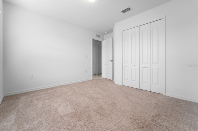 unfurnished bedroom with light colored carpet and a closet