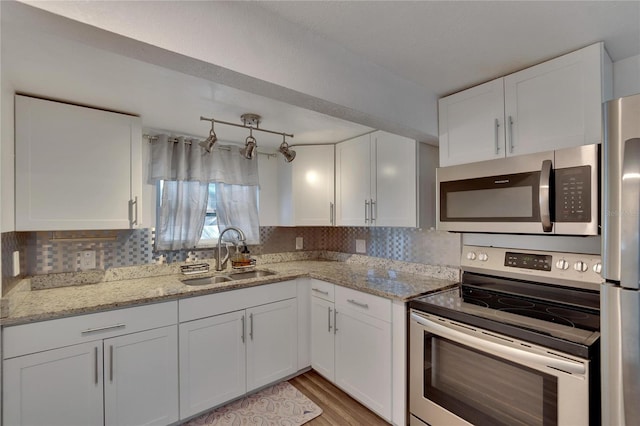 kitchen with light stone countertops, sink, white cabinets, and appliances with stainless steel finishes