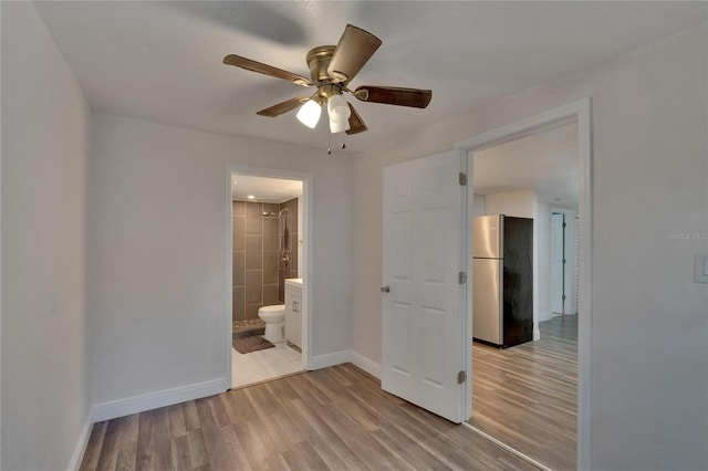 unfurnished bedroom with ceiling fan, light hardwood / wood-style floors, stainless steel refrigerator, and ensuite bath