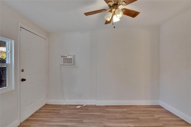 spare room with a wall mounted air conditioner, ceiling fan, and light hardwood / wood-style flooring