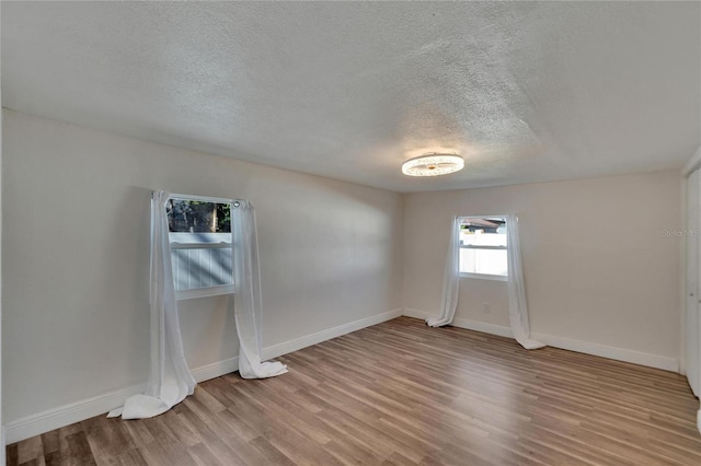 spare room featuring a textured ceiling and light wood-type flooring