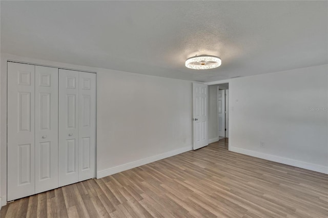 unfurnished bedroom featuring a closet, a textured ceiling, and light wood-type flooring