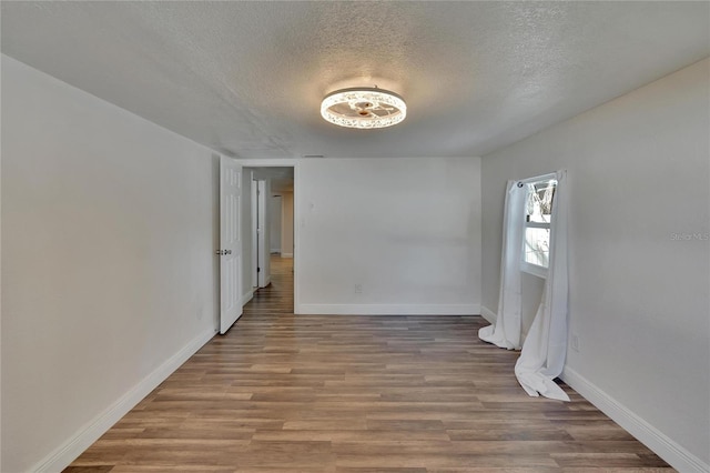 unfurnished room featuring light wood-type flooring and a textured ceiling