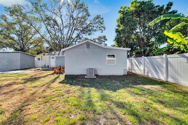 rear view of house featuring central air condition unit and a lawn