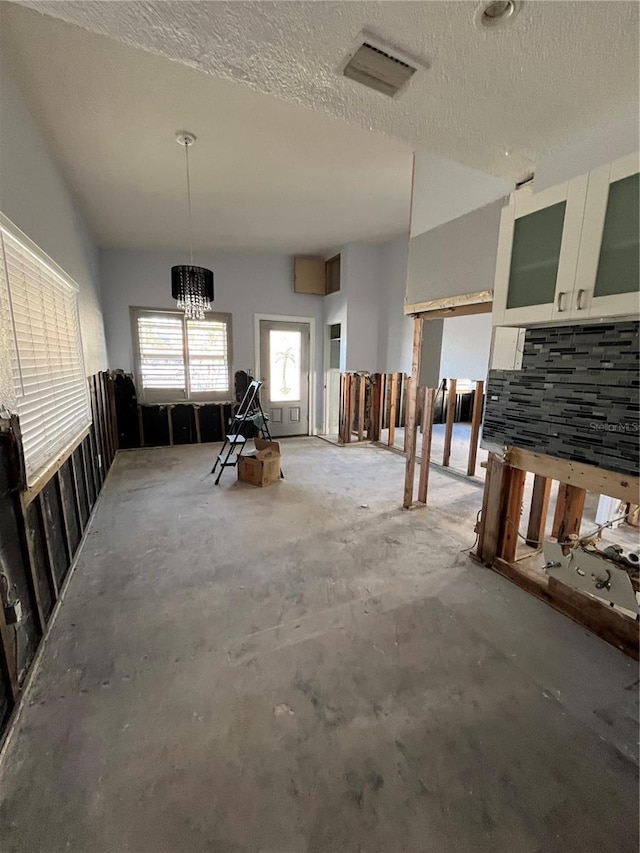 misc room featuring concrete floors, a textured ceiling, and a notable chandelier