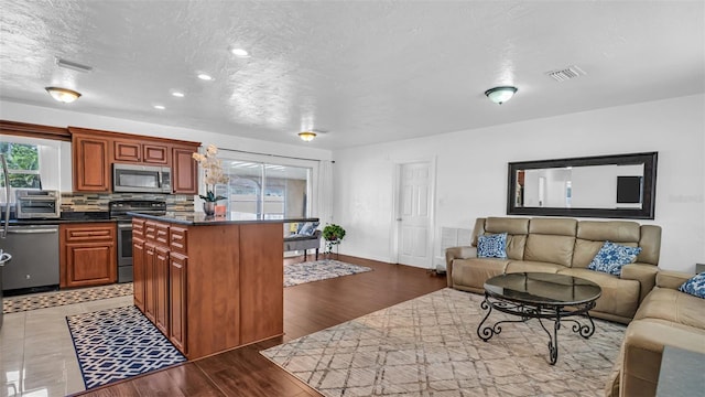 kitchen featuring decorative backsplash, stainless steel appliances, a kitchen island, and dark hardwood / wood-style floors