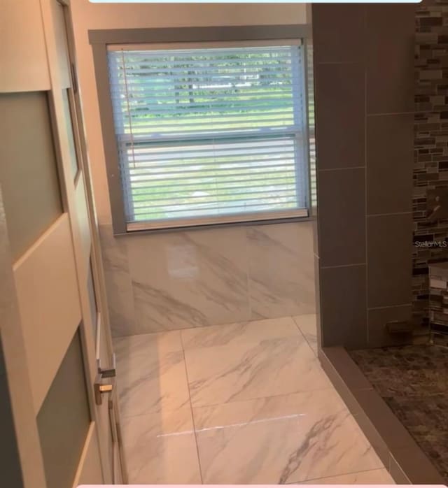 bathroom featuring a shower and tile walls