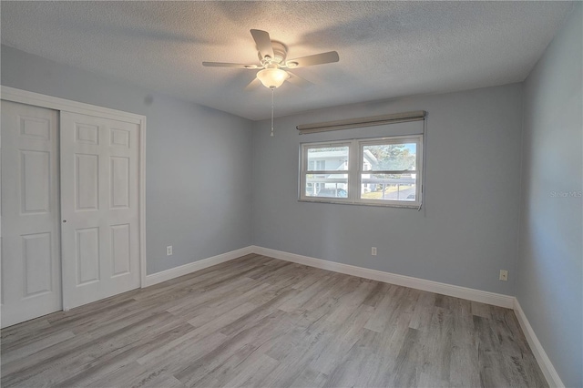 unfurnished bedroom featuring a textured ceiling, light wood-type flooring, a closet, and ceiling fan